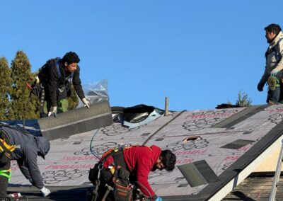 Four workers installing and asphalt shingle roof